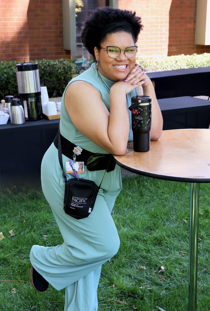 Regency Jakara Smith smiling outdoors, leaning on a table